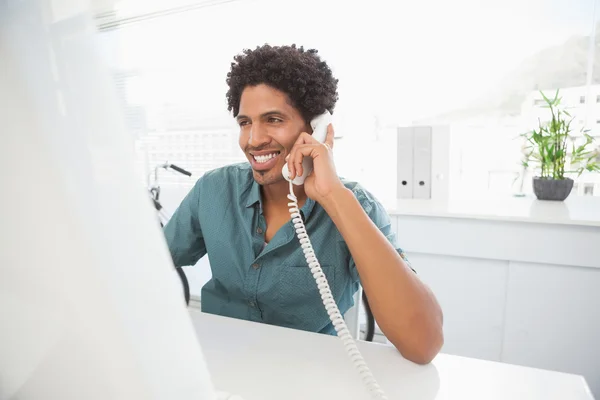 Handsome businessman talking on phone at desk — Stock Photo, Image