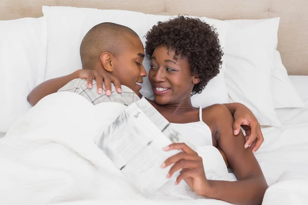 Happy couple lying in bed cuddling — Stock Photo, Image
