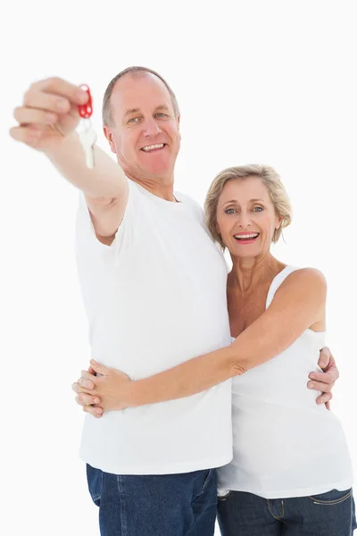 Couple d'âge mûr souriant à la caméra avec nouvelle clé de la maison — Photo