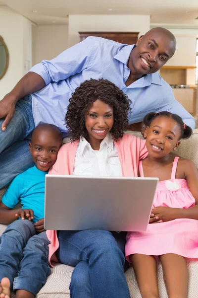 Gelukkige familie ontspannen op de Bank met behulp van laptop — Stockfoto