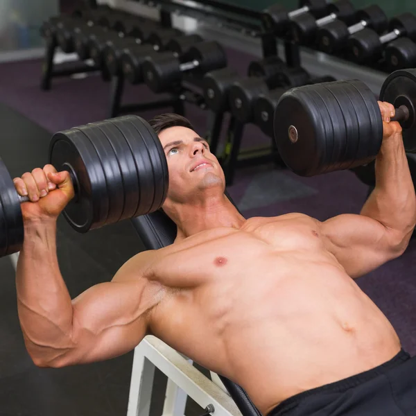 Uomo muscolare che si esercita con i manubri in palestra — Foto Stock