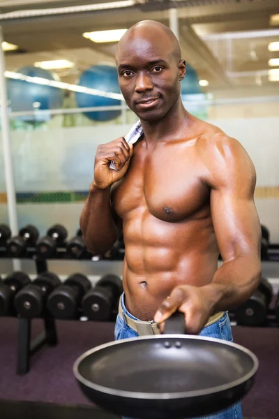 Muscular man holding frying pan in gym — Stock Photo, Image