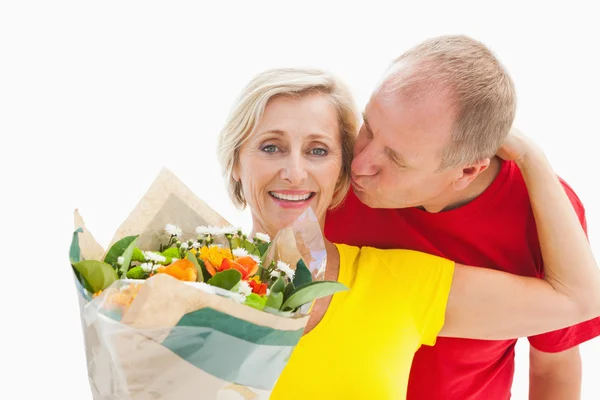 Mogen man kysser hans partner holding blommor — Stockfoto