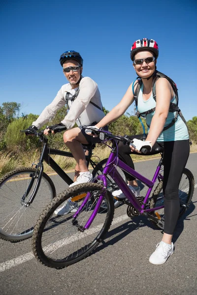 Pareja feliz activa que va a dar un paseo en bicicleta en el campo —  Fotos de Stock