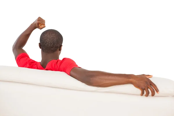 Mann im roten Trikot sitzt auf Couch und jubelt — Stockfoto
