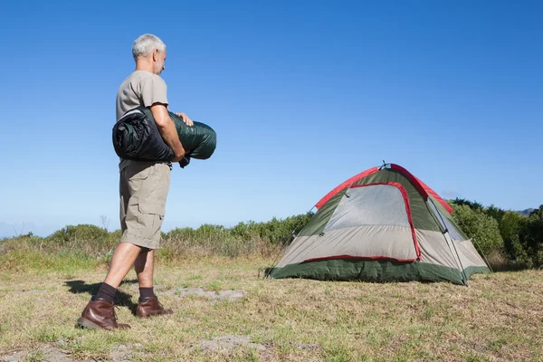 Camper feliz caminando hacia su tienda sosteniendo el saco de dormir —  Fotos de Stock