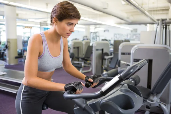 Ajuste morena haciendo ejercicio en la bicicleta estática — Foto de Stock