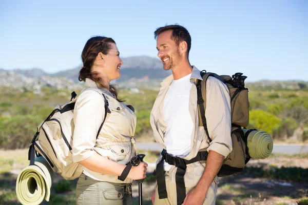 Hiking couple smiling at each other in the countryside — Stock Photo, Image