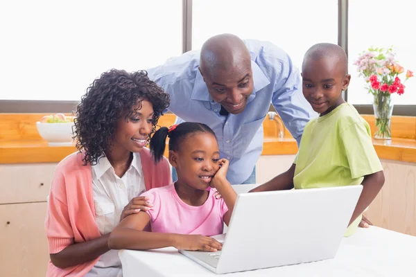 Irmãos bonitos usando laptop junto com os pais — Fotografia de Stock