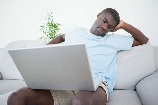 Casual man sitting on sofa using laptop — Stock Photo, Image