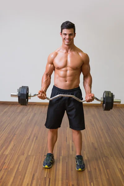 Uomo muscoloso senza maglietta che solleva il bilanciere in palestra — Foto Stock