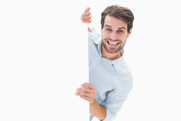 Attractive young man smiling and holding poster — Stock Photo, Image