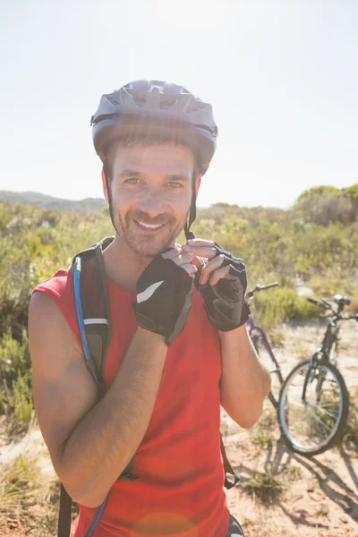 Fit cyclist adjusting helmet strap on country terrain — Stock Photo, Image