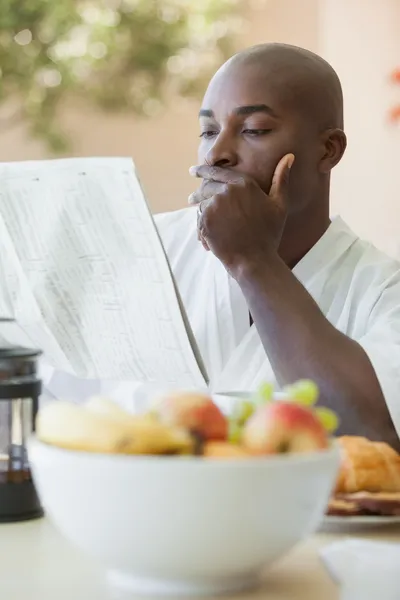 Mann im Bademantel liest Zeitung und frühstückt auf der Terrasse — Stockfoto