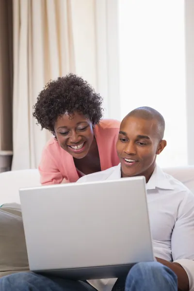 Par avkopplande i soffan med laptop — Stockfoto