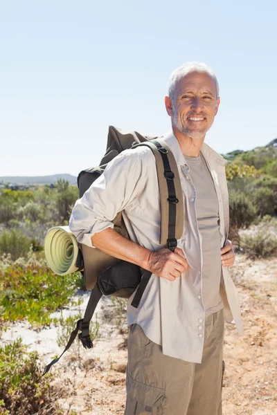 Handsome hiker smiling at camera in the countryside — Stock Photo, Image