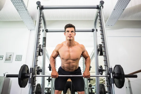 Shirtless muscular man lifting barbell in gym — Stock Photo, Image