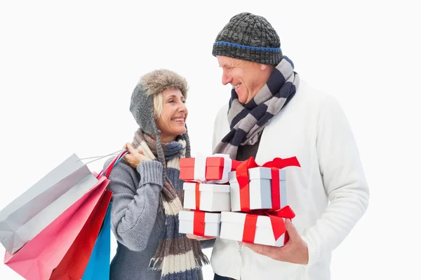 Mature couple in winter clothes holding gifts — Stock Photo, Image