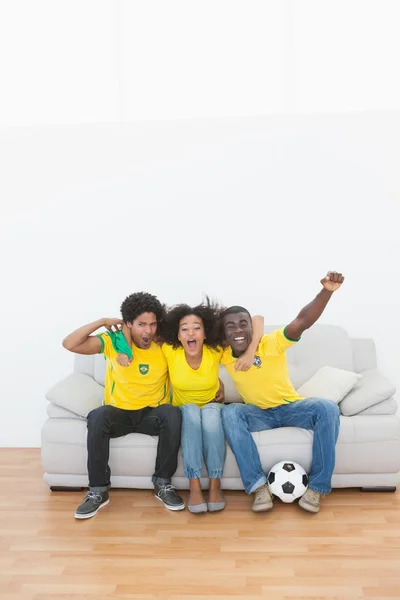 Brasilianische Fußballfans sitzen auf Couch und jubeln gemeinsam — Stockfoto