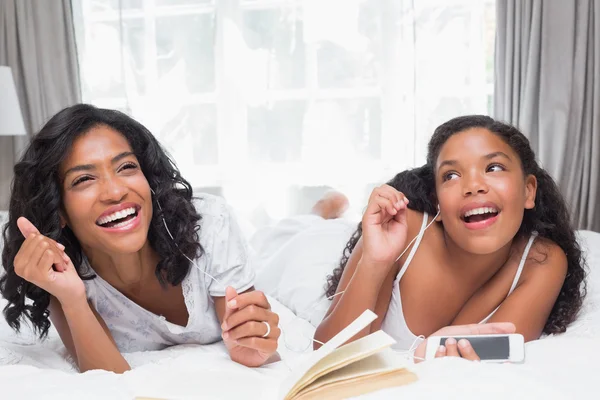 Mãe e filha lendo livro e ouvindo música — Fotografia de Stock