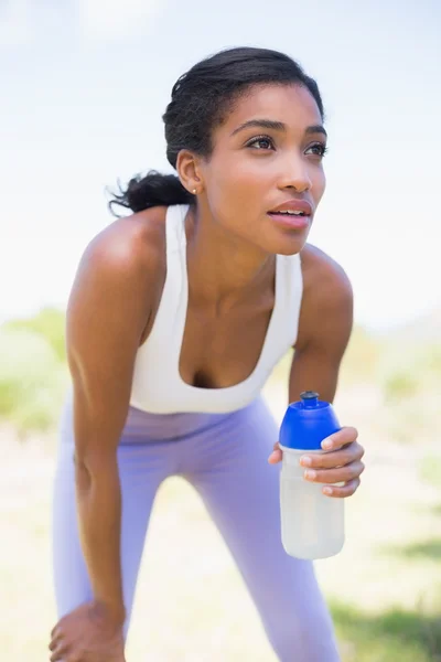 Fit woman holding sports bottle smiling — Stock Photo, Image