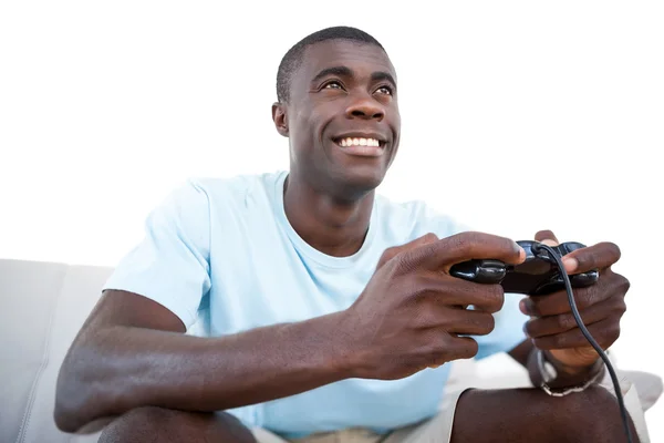 Sorrindo homem sentado no sofá jogando videogames — Fotografia de Stock