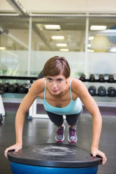 Fit brunette en utilisant la balle bosu en position de planche — Photo