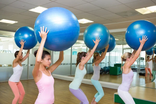 Fitness class holding up exercise balls in studio — Stock Photo, Image