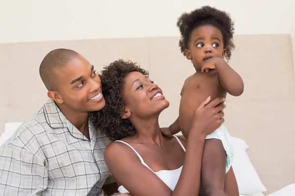 Lyckliga paret sitter på sängen med baby dotter — Stockfoto