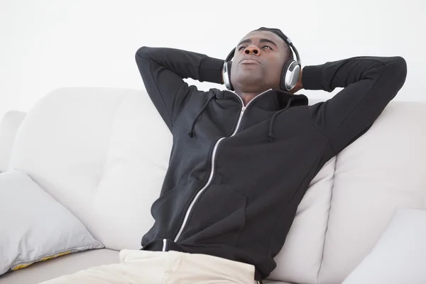 Homme décontracté assis sur son canapé à écouter de la musique — Photo