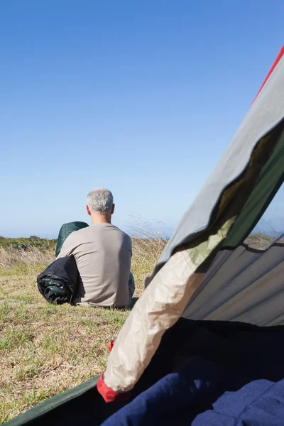 Счастливый турист сидит у палатки, держа спальный мешок. — стоковое фото