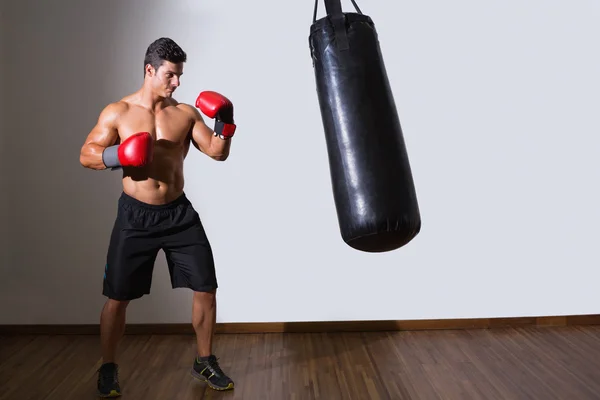 Gömleksiz kas boksör ile kum torbası içinde jimnastik salonu — Stok fotoğraf