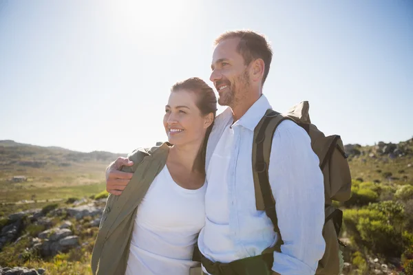 Pareja de senderismo abrazando y sonriendo en terreno campestre — Foto de Stock