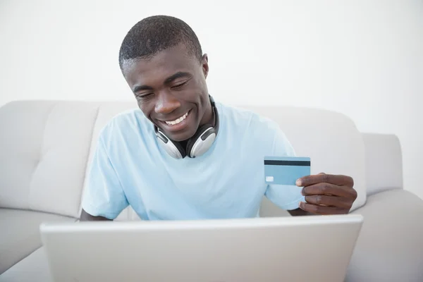 Hombre casual sentado en el sofá utilizando el ordenador portátil para comprar en línea — Foto de Stock