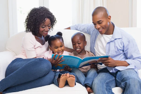 Família feliz no sofá lendo livro de histórias — Fotografia de Stock