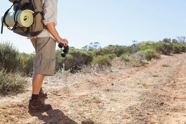 Hiker håller sin kikare på land trail — Stockfoto