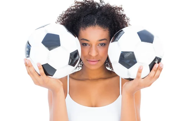 Chica bonita sosteniendo balones de fútbol y mirando a la cámara — Foto de Stock
