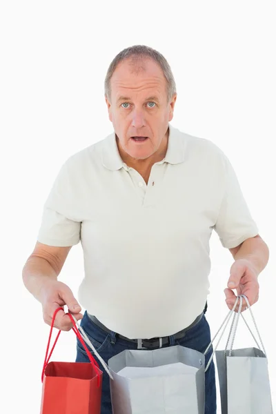 Mature man feeling buyers remorse holding bags — Stock Photo, Image