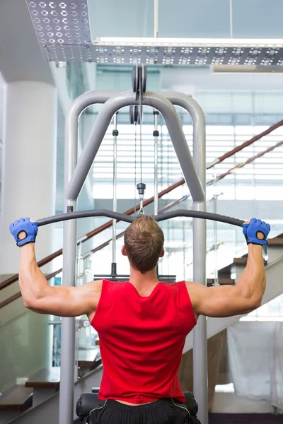 Strong man using weights machine for arms — Stock Photo, Image