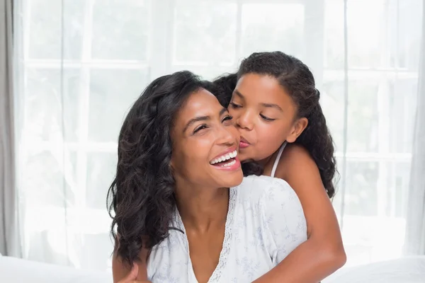 Sonrientes madre e hija posando juntas en la cama —  Fotos de Stock