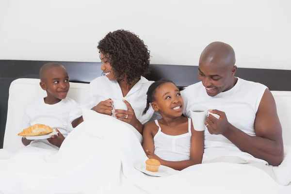 Familia relajándose juntos en la cama desayunando —  Fotos de Stock