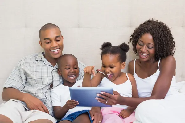 Šťastná rodina společně pomocí tabletu na posteli — Stock fotografie