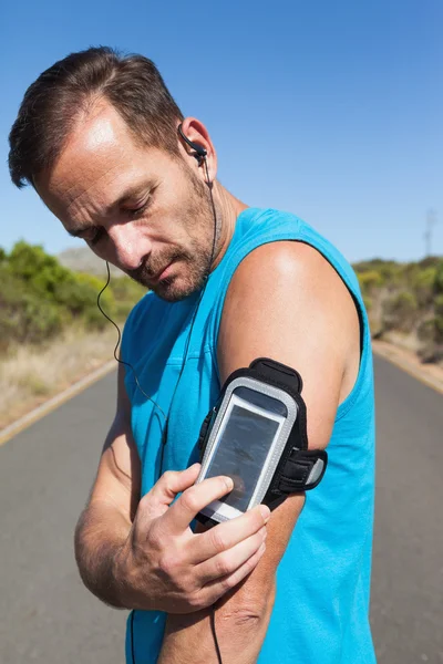 Homme athlétique changer la musique sur une course — Photo