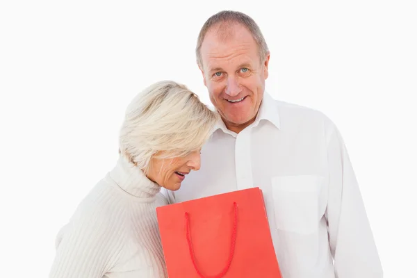 Pareja mayor sosteniendo bolsa de regalo roja — Foto de Stock