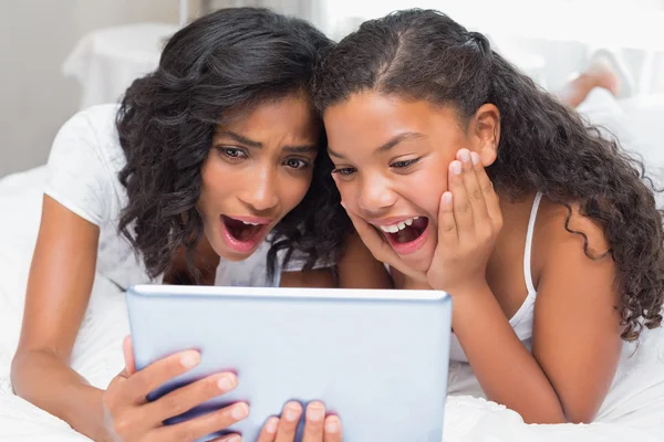 Surprised mother and daughter using tablet together — Stock Photo, Image