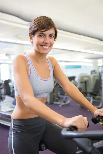 Brune souriante travaillant sur le cross trainer — Photo