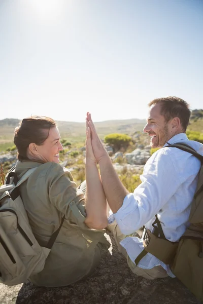 Pareja de senderismo sentada en terreno montañoso chocando los cinco — Foto de Stock