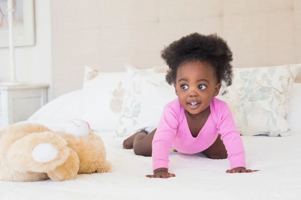 Menina bebê em babygro rosa rastejando na cama — Fotografia de Stock