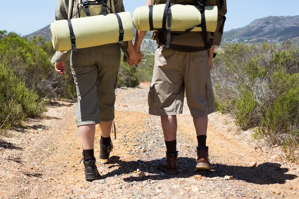 Pareja de senderismo caminando por sendero de montaña cogidos de la mano — Foto de Stock