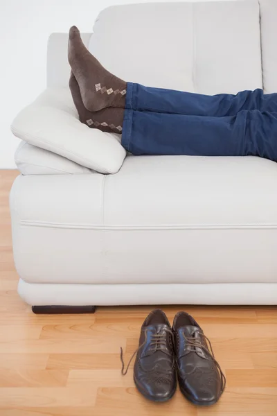 Уставший бизнесмен лежит на диване без обуви — стоковое фото